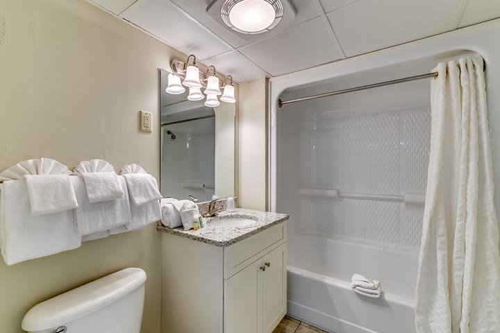 A clean bathroom with a toilet, sink, and tub/shower.