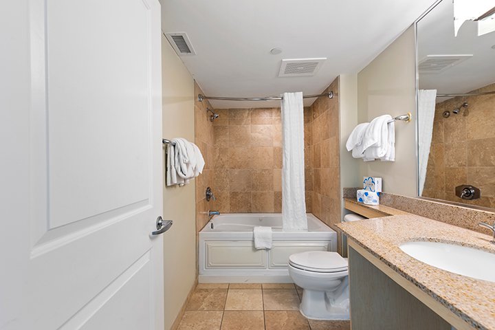 A standard hotel bathroom with a toilet, sink, bathtub, and shower.