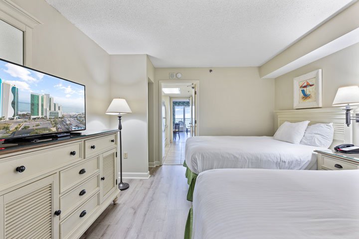 A hotel room with two beds, a TV, and a dresser.