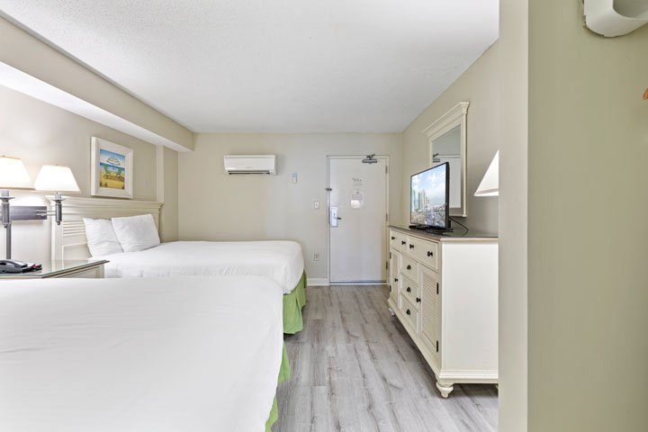 A hotel room with two beds, a dresser, TV, and lamps.