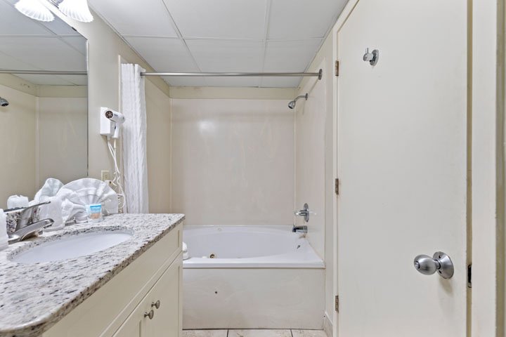 a bathroom with a granite countertop sink and a bathtub