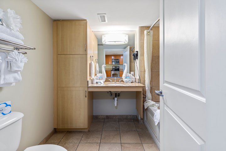 A bathroom with a toilet, sink, and wooden cabinet