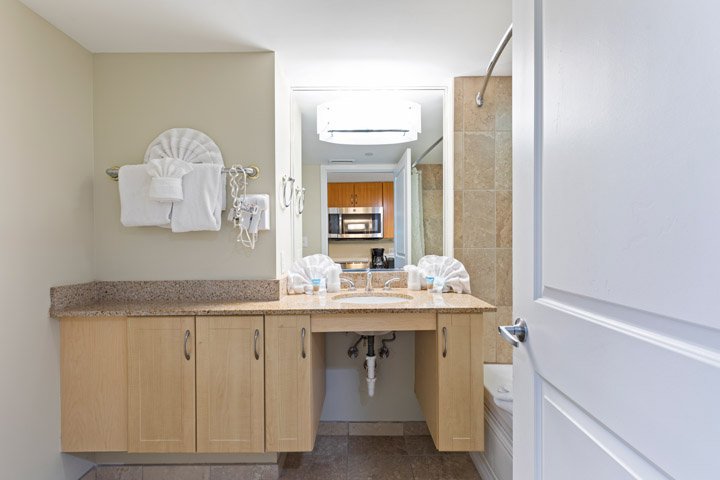 A clean and well-appointed bathroom with a double vanity, granite countertops, and light wood cabinets.