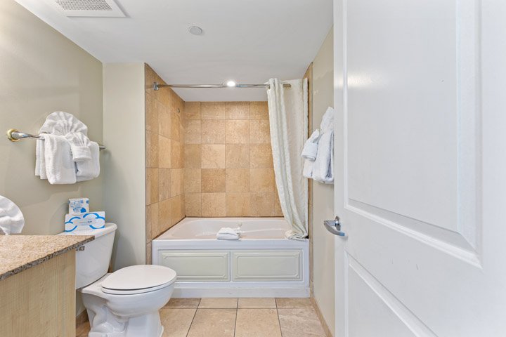 a bathroom with a toilet, bathtub, and granite countertop