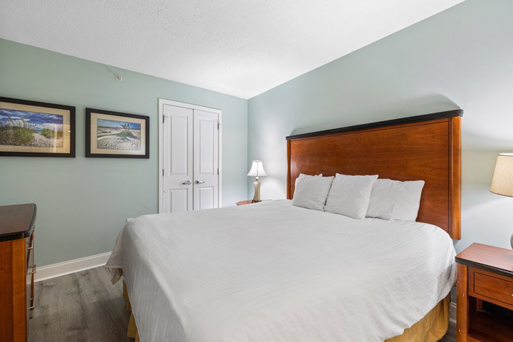 A hotel room with a large bed, nightstands, and a door.
