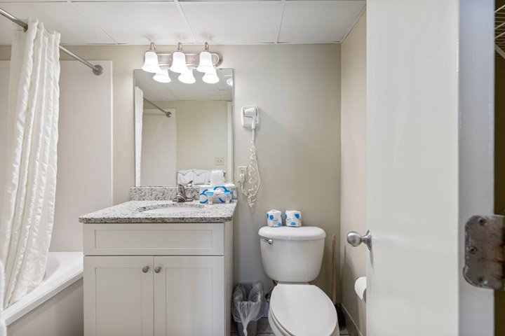 A clean and simple bathroom with a granite countertop, white cabinets, and a single sink.
