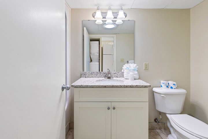 A standard bathroom with a granite countertop, white cabinets, and beige walls.