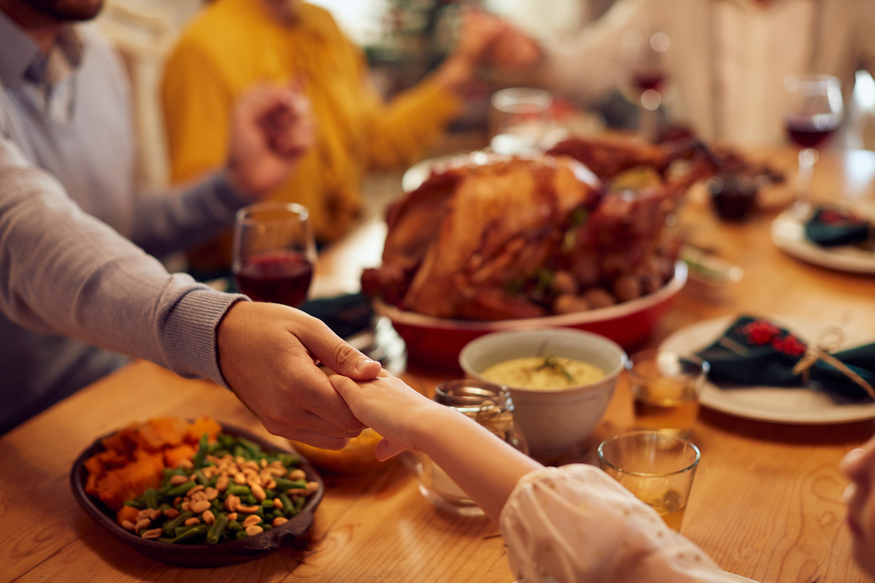 A close-up of a hand holding another hand across a table with food